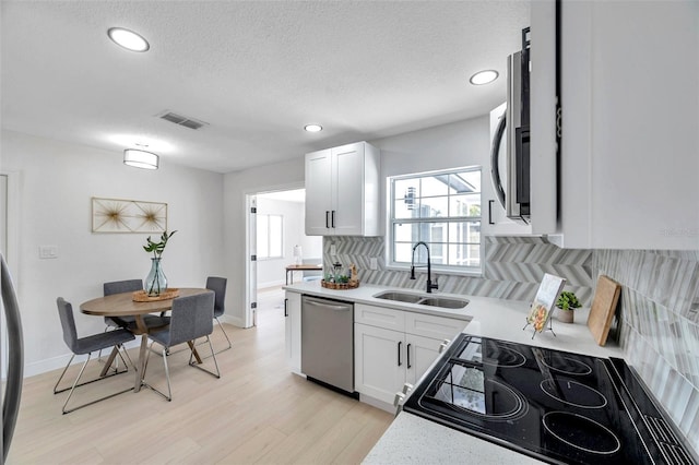 8045 Colton Dr, Port Richey, FL 34668 - kitchen featuring stainless steel appliances, tasteful backsplash, light countertops, light wood-style flooring, and white cabinetry