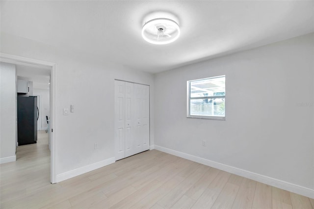 8045 Colton Dr, Port Richey, FL 34668 - unfurnished bedroom featuring freestanding refrigerator, light wood-style floors, and a closet