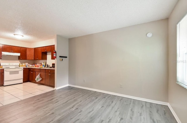 7920 N Marks St, Tampa, FL 33604 - kitchen featuring electric stove, under cabinet range hood, a textured ceiling, light wood-type flooring, and light countertops