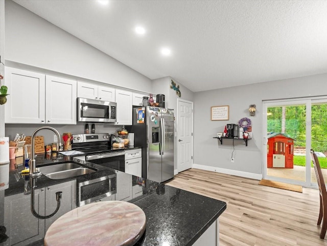 8737 N Spikes Way, Dunnellon, FL 34434 - kitchen featuring stainless steel appliances, vaulted ceiling, light wood finished floors, dark stone counters, and white cabinets