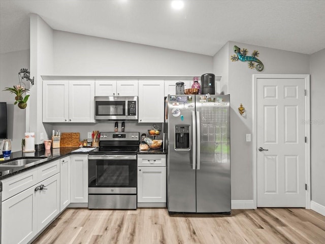8737 N Spikes Way, Dunnellon, FL 34434 - kitchen with stainless steel appliances, lofted ceiling, light wood-type flooring, white cabinetry, and dark stone counters