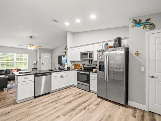8737 N Spikes Way, Dunnellon, FL 34434 - kitchen featuring stainless steel appliances, a peninsula, dark countertops, lofted ceiling, and light wood-style floors