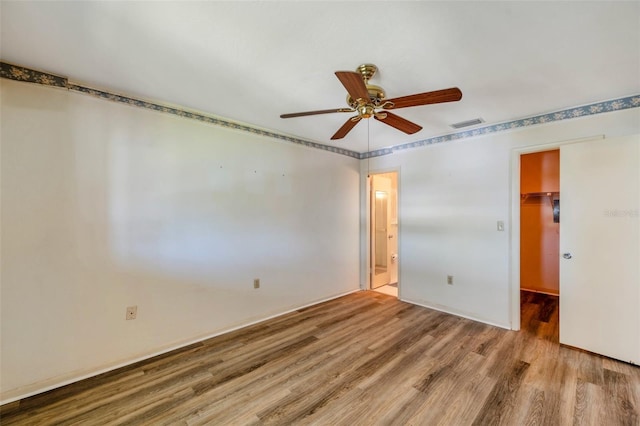 8396 111th St Unit 301, Seminole, FL 33772 - unfurnished bedroom with wood finished floors, a walk in closet, a closet, ensuite bath, and ceiling fan