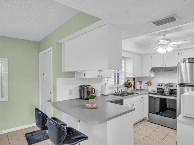 1250 S Pinellas Ave Unit 207, Tarpon Springs, FL 34689 - kitchen with appliances with stainless steel finishes, a peninsula, light tile patterned floors, backsplash, and white cabinetry