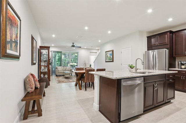 5808 Grand Sonata Ave, Lutz, FL 33558 - kitchen with appliances with stainless steel finishes, recessed lighting, dark brown cabinets, ceiling fan, and light stone counters