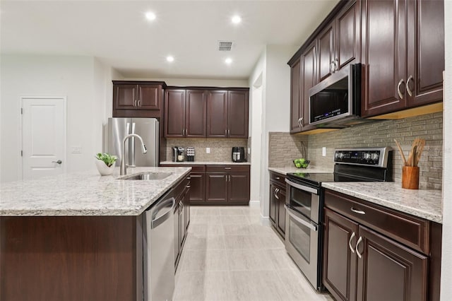 5808 Grand Sonata Ave, Lutz, FL 33558 - kitchen with stainless steel appliances, backsplash, a kitchen island with sink, dark brown cabinets, and recessed lighting