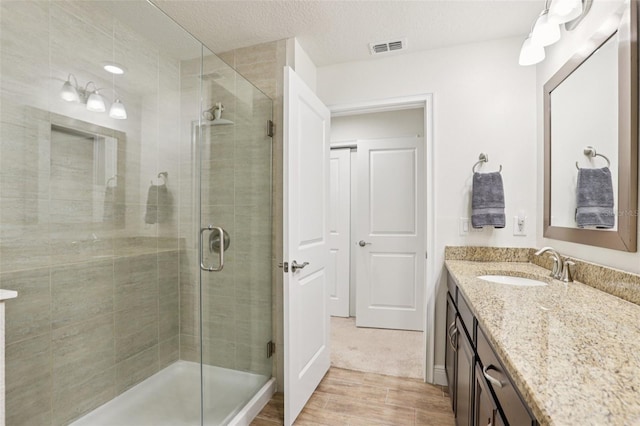 5808 Grand Sonata Ave, Lutz, FL 33558 - bathroom featuring vanity, a shower stall, wood finished floors, and a textured ceiling
