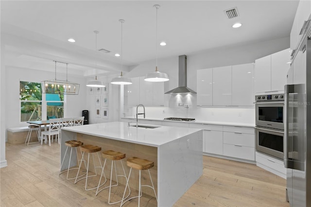 503 W Davis Blvd, Tampa, FL 33606 - kitchen with appliances with stainless steel finishes, wall chimney exhaust hood, modern cabinets, white cabinets, and an island with sink