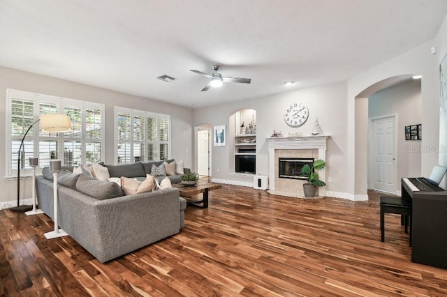 15217 Octavia Ln, Odessa, FL 33556 - living room featuring arched walkways, wood finished floors, a ceiling fan, and a tiled fireplace