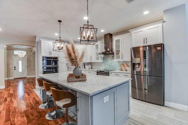 15217 Octavia Ln, Odessa, FL 33556 - kitchen with appliances with stainless steel finishes, wall chimney exhaust hood, arched walkways, a kitchen island, and a chandelier