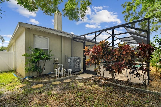 15217 Octavia Ln, Odessa, FL 33556 - back of house with stucco siding, a chimney, a patio, and glass enclosure