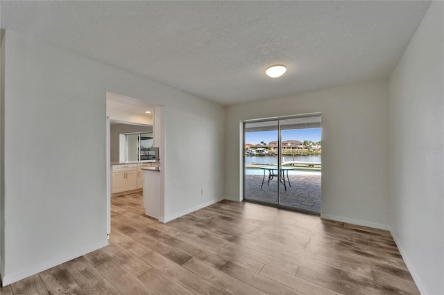 6334 Cocoa Ln, Apollo Beach, FL 33572 - spare room with light wood-style floors, a textured ceiling, and a water view
