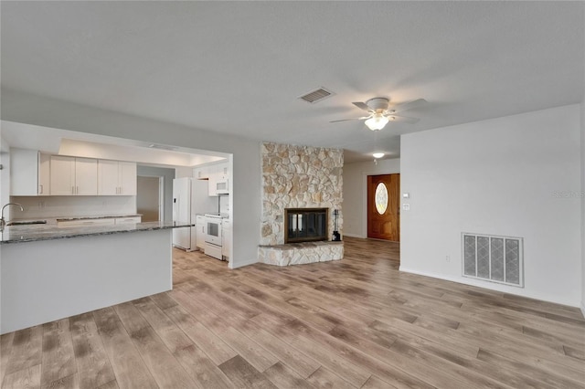 6334 Cocoa Ln, Apollo Beach, FL 33572 - unfurnished living room featuring light wood-style flooring, ceiling fan, and a stone fireplace