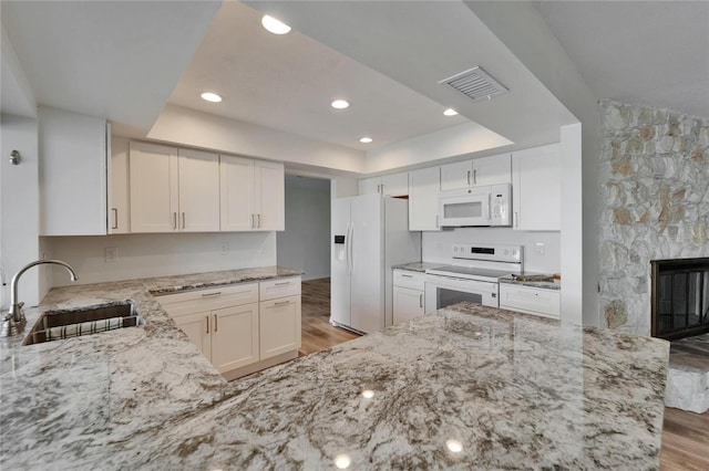 6334 Cocoa Ln, Apollo Beach, FL 33572 - kitchen with white appliances, a tray ceiling, light wood-style floors, light stone countertops, and recessed lighting