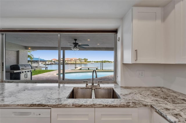 6334 Cocoa Ln, Apollo Beach, FL 33572 - kitchen featuring white dishwasher, white cabinets, a water view, light stone counters, and a ceiling fan