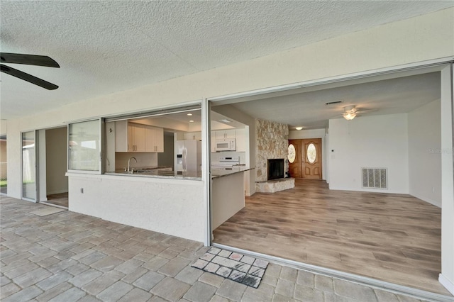 6334 Cocoa Ln, Apollo Beach, FL 33572 - kitchen featuring a ceiling fan, white appliances, open floor plan, a stone fireplace, and a peninsula