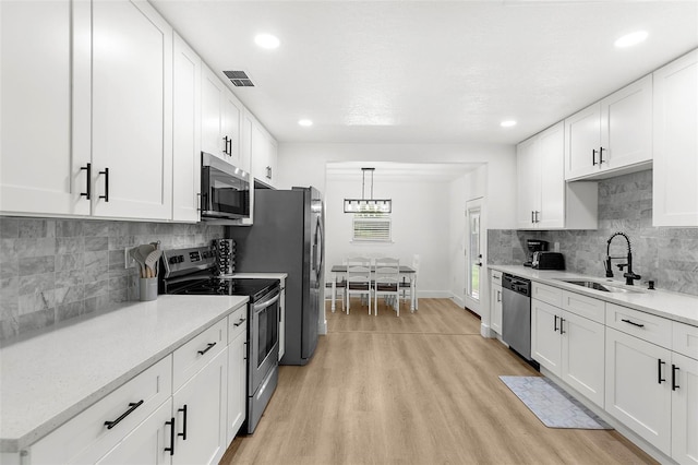 1275 Palm St, Clearwater, FL 33755 - kitchen featuring stainless steel appliances, light wood-type flooring, white cabinets, tasteful backsplash, and recessed lighting