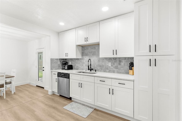 1275 Palm St, Clearwater, FL 33755 - kitchen featuring stainless steel dishwasher, light countertops, decorative backsplash, white cabinetry, and light wood-style floors