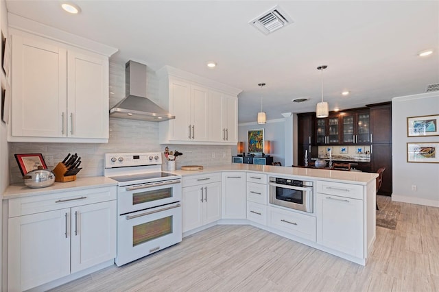 1060 N Shore Dr NE Unit 6, Saint Petersburg, FL 33701 - kitchen with double oven range, wall chimney range hood, a peninsula, decorative backsplash, and light countertops