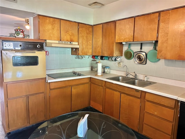 1605 Logan St, Clearwater, FL 33755 - kitchen with white oven, black electric cooktop, under cabinet range hood, brown cabinetry, and light countertops