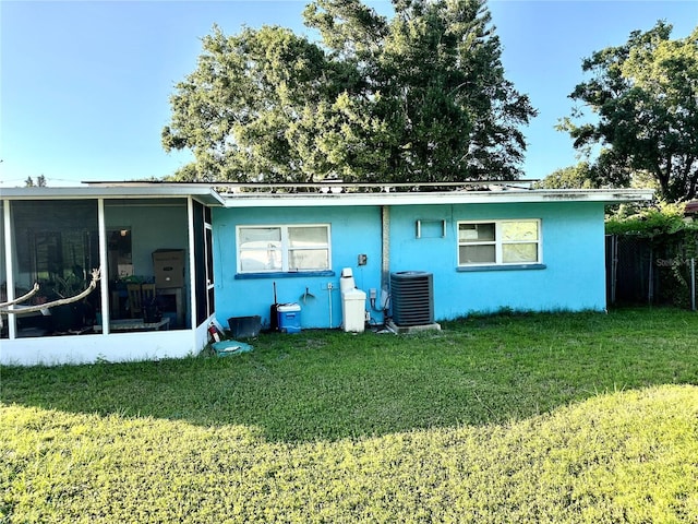 1605 Logan St, Clearwater, FL 33755 - back of house featuring a sunroom, a lawn, and stucco siding