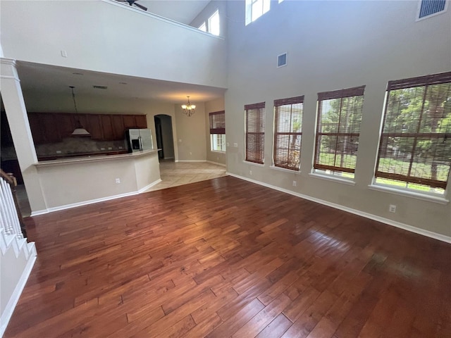 405 Islebay Dr, Apollo Beach, FL 33572 - unfurnished living room with a chandelier, wood-type flooring, arched walkways, and a high ceiling