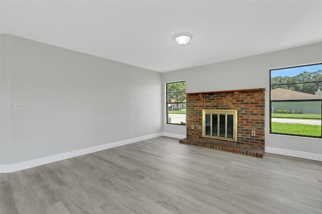 2151 Groveglen Ln S, Lakeland, FL 33813 - unfurnished living room featuring wood finished floors, plenty of natural light, and a brick fireplace