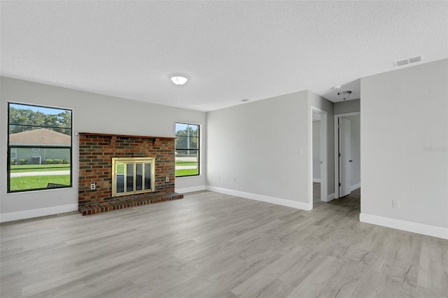 2151 Groveglen Ln S, Lakeland, FL 33813 - unfurnished living room with wood finished floors, plenty of natural light, a brick fireplace, and a textured ceiling