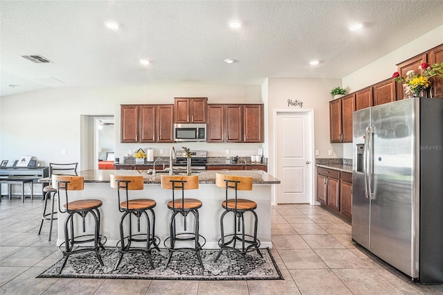 10211 Cakebread Ln, Riverview, FL 33578 - kitchen featuring appliances with stainless steel finishes, a kitchen bar, a kitchen island with sink, stone counters, and recessed lighting