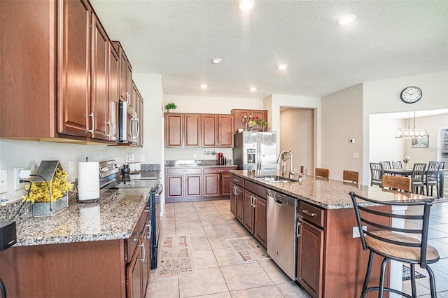 10211 Cakebread Ln, Riverview, FL 33578 - kitchen featuring appliances with stainless steel finishes, a kitchen breakfast bar, a kitchen island with sink, light tile patterned floors, and recessed lighting
