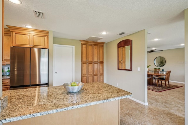 2110 W View Dr, Sun City Center, FL 33573 - kitchen with stainless steel fridge, light stone counters, recessed lighting, light tile patterned floors, and brown cabinetry