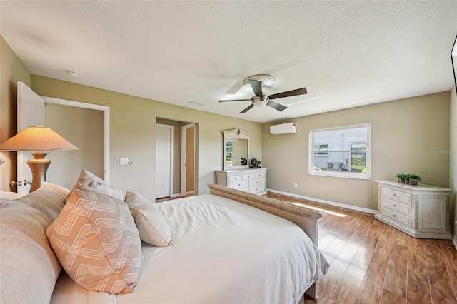 2110 W View Dr, Sun City Center, FL 33573 - bedroom featuring wood finished floors, a wall mounted AC, a textured ceiling, and a ceiling fan