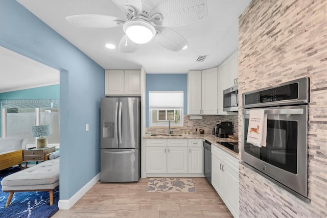 4718 24th Ave S, Saint Petersburg, FL 33711 - kitchen with appliances with stainless steel finishes, white cabinets, ceiling fan, backsplash, and light wood-style flooring