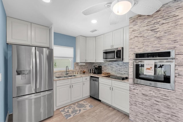 4718 24th Ave S, Saint Petersburg, FL 33711 - kitchen featuring appliances with stainless steel finishes, light wood-style flooring, white cabinets, tasteful backsplash, and recessed lighting