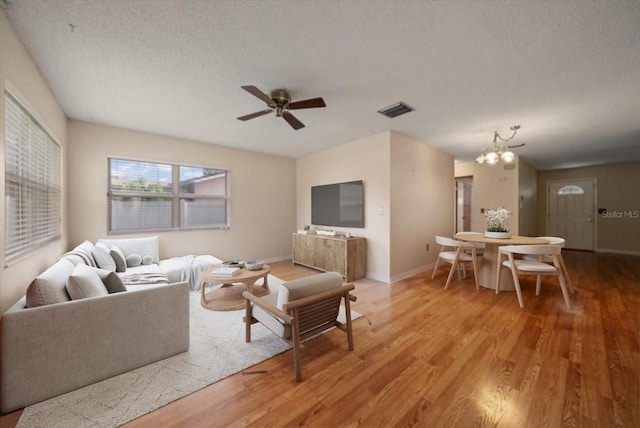 6530 68th St N, Pinellas Park, FL 33781 - living area with a chandelier, light wood finished floors, a textured ceiling, and a ceiling fan