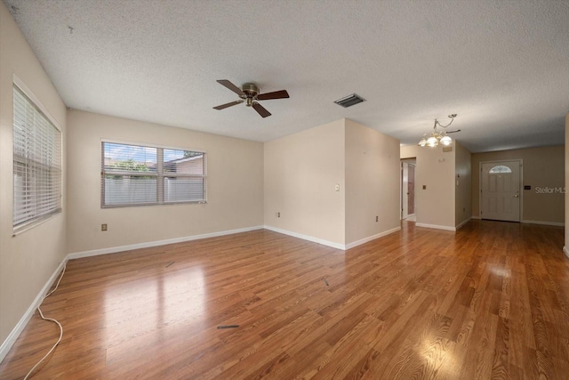 6530 68th St N, Pinellas Park, FL 33781 - empty room featuring a chandelier, a textured ceiling, light wood-style floors, and a ceiling fan