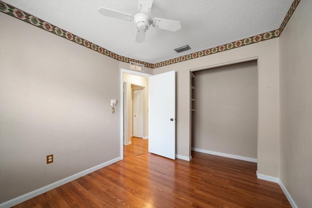 6530 68th St N, Pinellas Park, FL 33781 - unfurnished bedroom featuring a textured ceiling, wood finished floors, a closet, and ceiling fan
