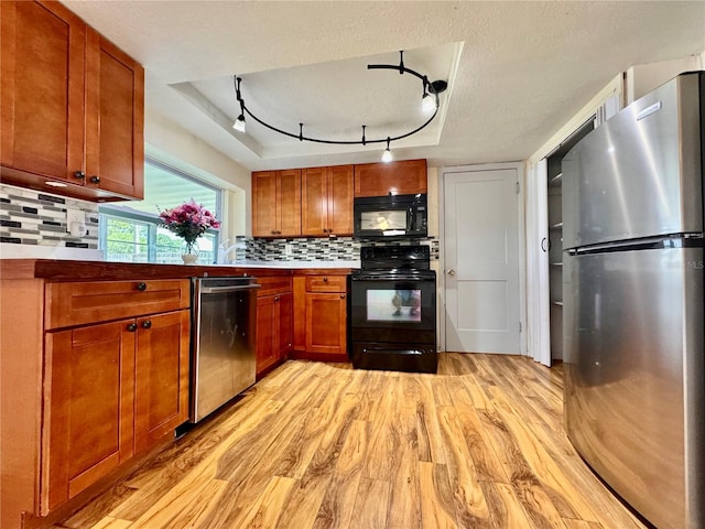 3902 Glissade Dr, New Port Richey, FL 34652 - kitchen featuring black appliances, light wood finished floors, tasteful backsplash, brown cabinetry, and rail lighting