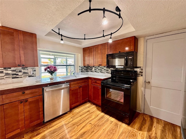 3902 Glissade Dr, New Port Richey, FL 34652 - kitchen with black appliances, a textured ceiling, a raised ceiling, light wood finished floors, and light countertops