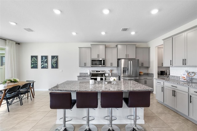 33675 Elm Hill Br, Wesley Chapel, FL 33545 - kitchen with stainless steel appliances, gray cabinets, tasteful backsplash, a kitchen island with sink, and recessed lighting
