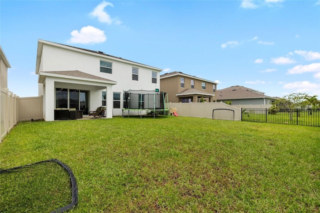 33675 Elm Hill Br, Wesley Chapel, FL 33545 - rear view of property with stucco siding, a trampoline, and a fenced backyard