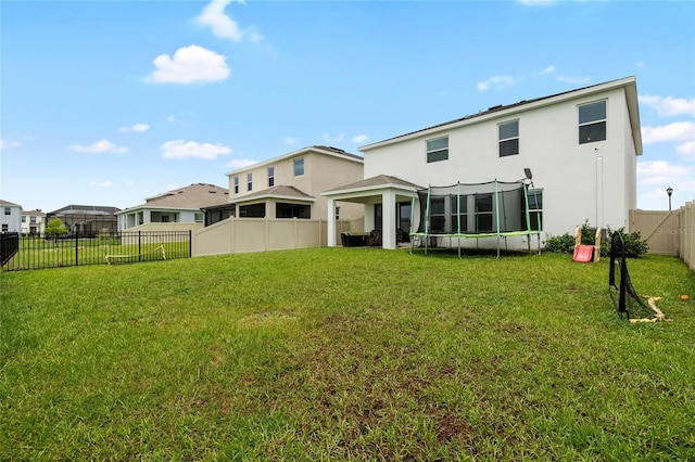 33675 Elm Hill Br, Wesley Chapel, FL 33545 - rear view of property with a trampoline, stucco siding, and a fenced backyard