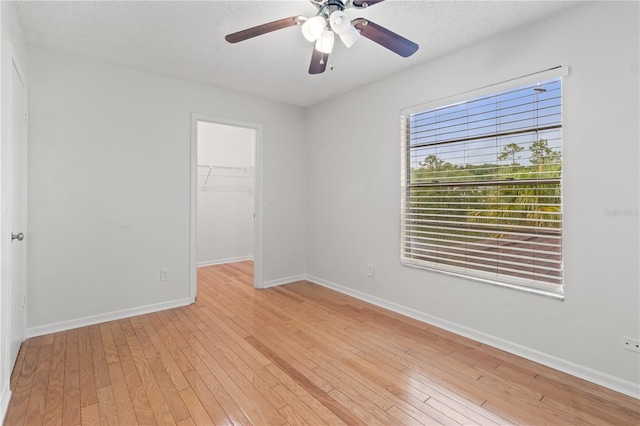 15636 Morning Dr, Lutz, FL 33559 - unfurnished bedroom featuring a walk in closet, light wood finished floors, a closet, and ceiling fan