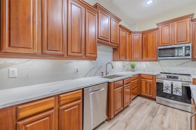 5224 Fairway One Dr, Valrico, FL 33596 - kitchen featuring stainless steel appliances, light stone counters, light wood finished floors, brown cabinetry, and backsplash
