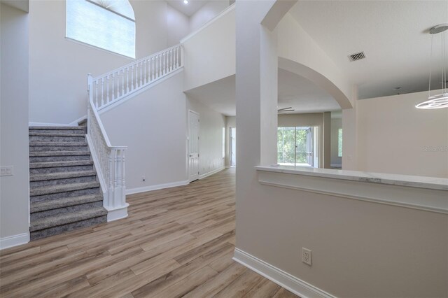 5224 Fairway One Dr, Valrico, FL 33596 - unfurnished living room with wood finished floors, stairway, arched walkways, a towering ceiling, and ceiling fan