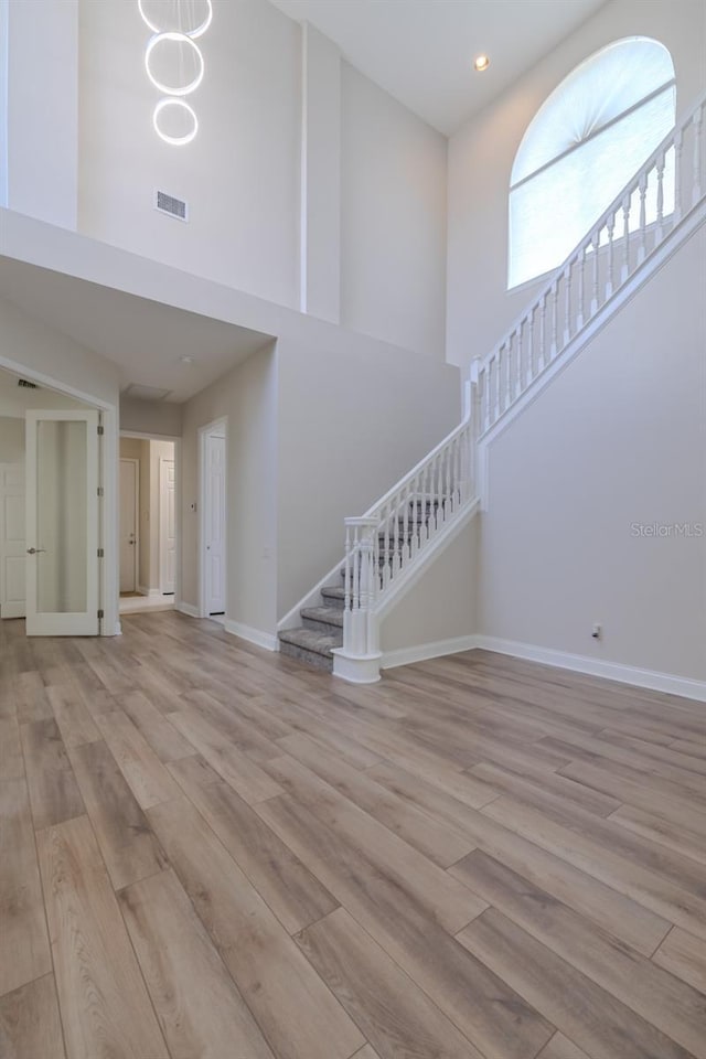 5224 Fairway One Dr, Valrico, FL 33596 - unfurnished living room with a towering ceiling, stairway, wood finished floors, and recessed lighting
