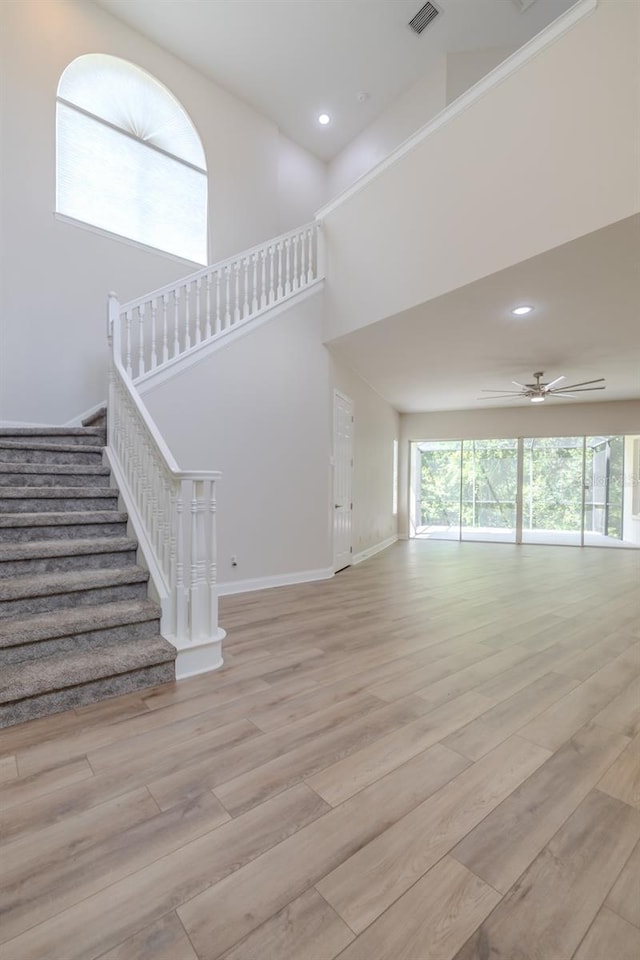 5224 Fairway One Dr, Valrico, FL 33596 - unfurnished living room with stairway, light wood finished floors, a ceiling fan, recessed lighting, and a towering ceiling