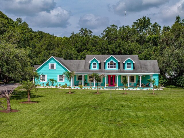 7427 20th St, Zephyrhills, FL 33540 - new england style home featuring covered porch, a front lawn, and a forest view