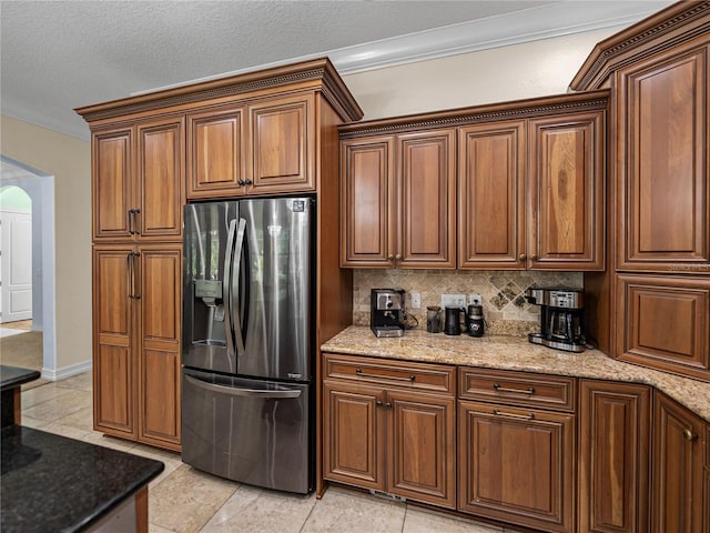 7427 20th St, Zephyrhills, FL 33540 - kitchen with stainless steel fridge, arched walkways, ornamental molding, light stone counters, and tasteful backsplash