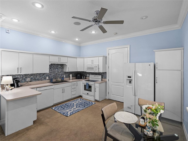 7427 20th St, Zephyrhills, FL 33540 - kitchen with white appliances, crown molding, white cabinetry, a peninsula, and light countertops